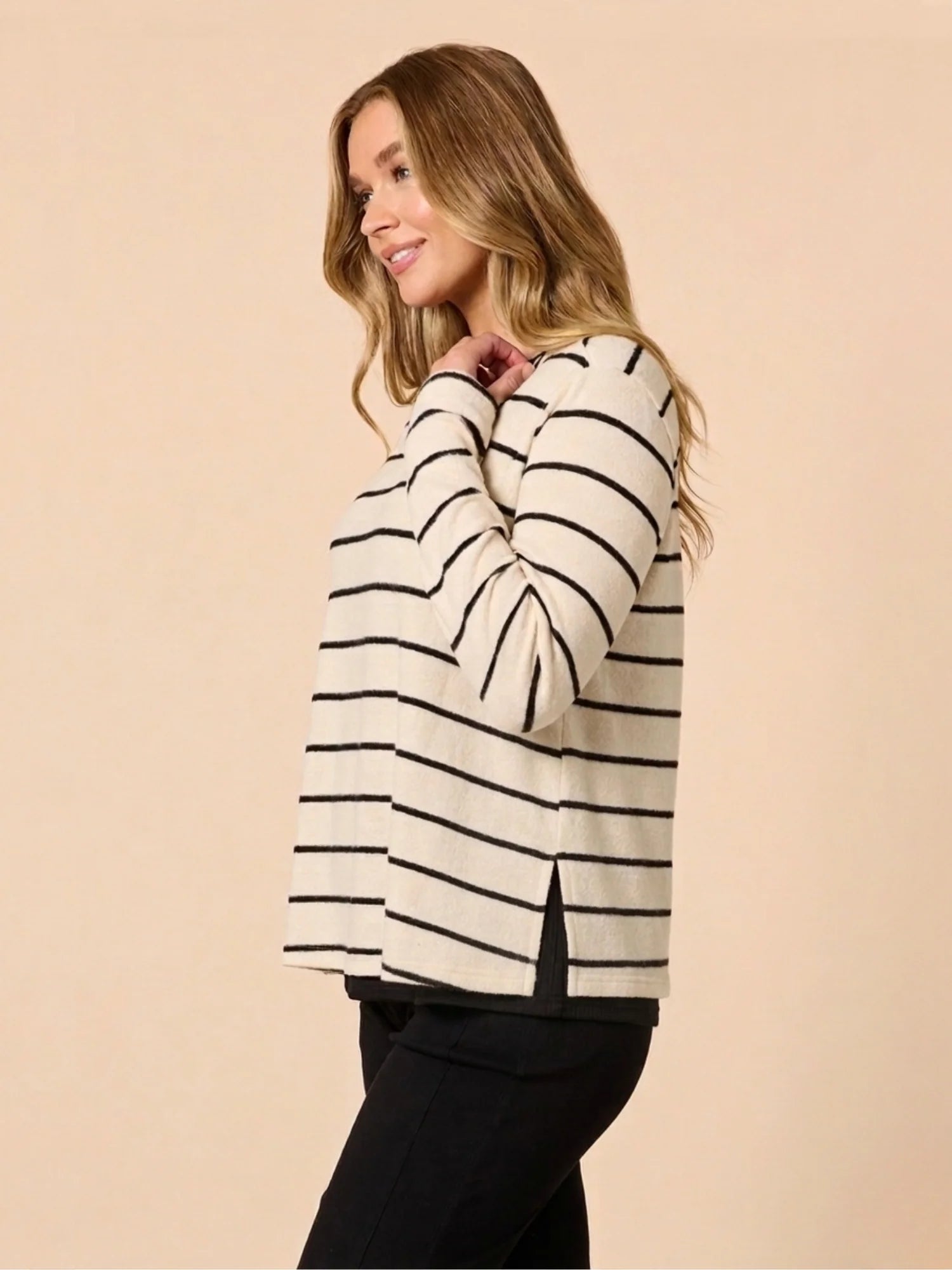 Image of Woman wearing a Threadz black and white striped sweater on a beige background