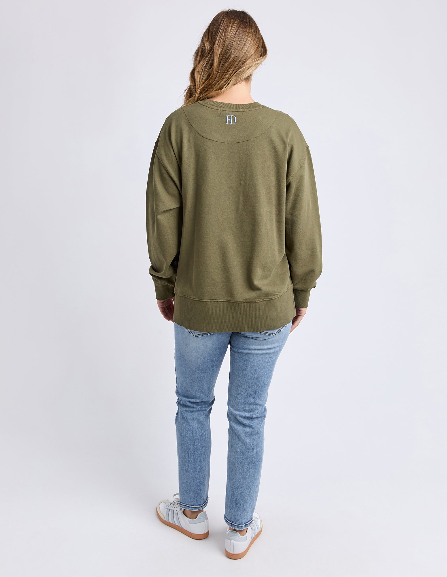 Collection of Person wearing an olive green jumper and light blue jeans on a white background in a gallery layout