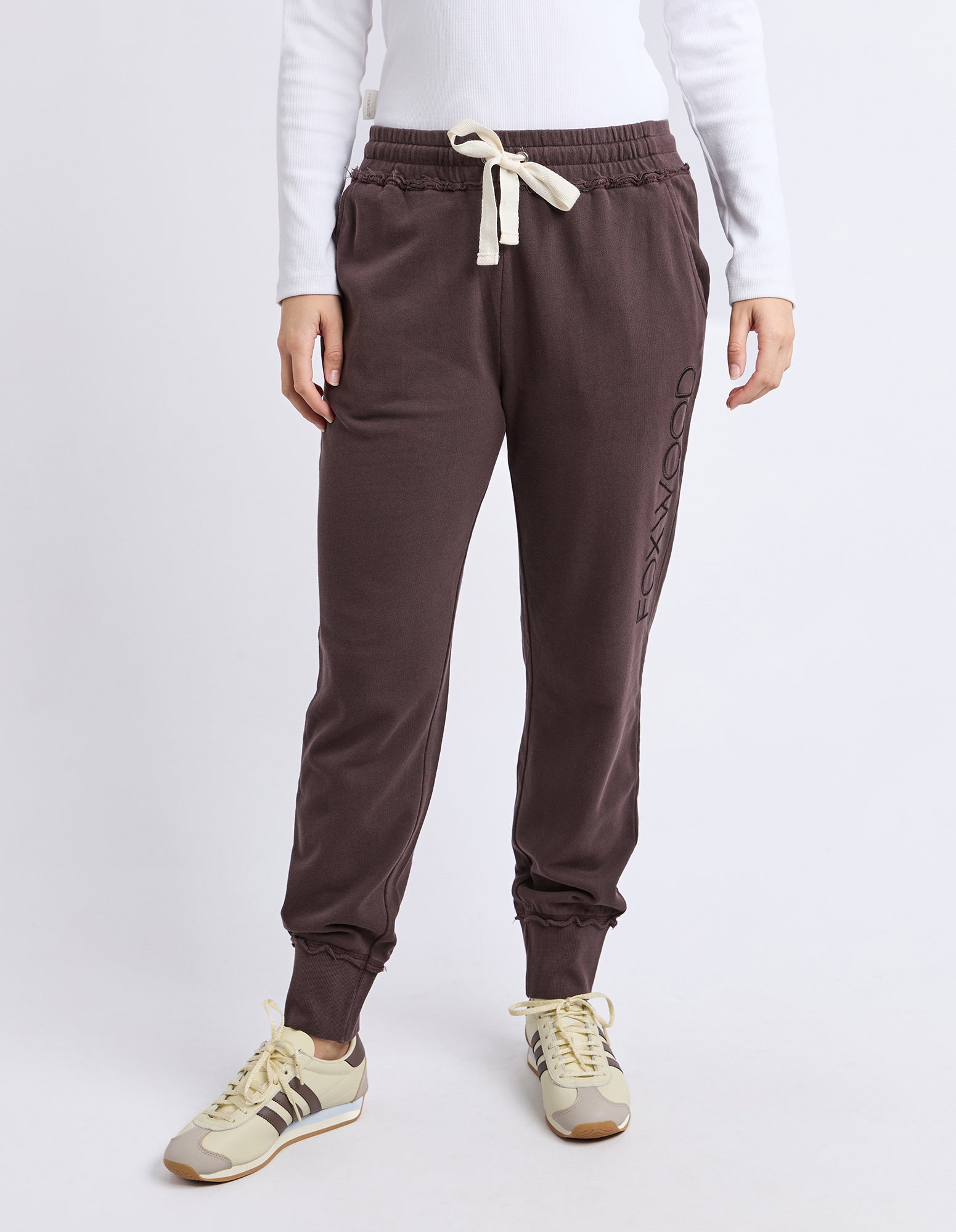 Image of Brown track pants with a logo on a white background