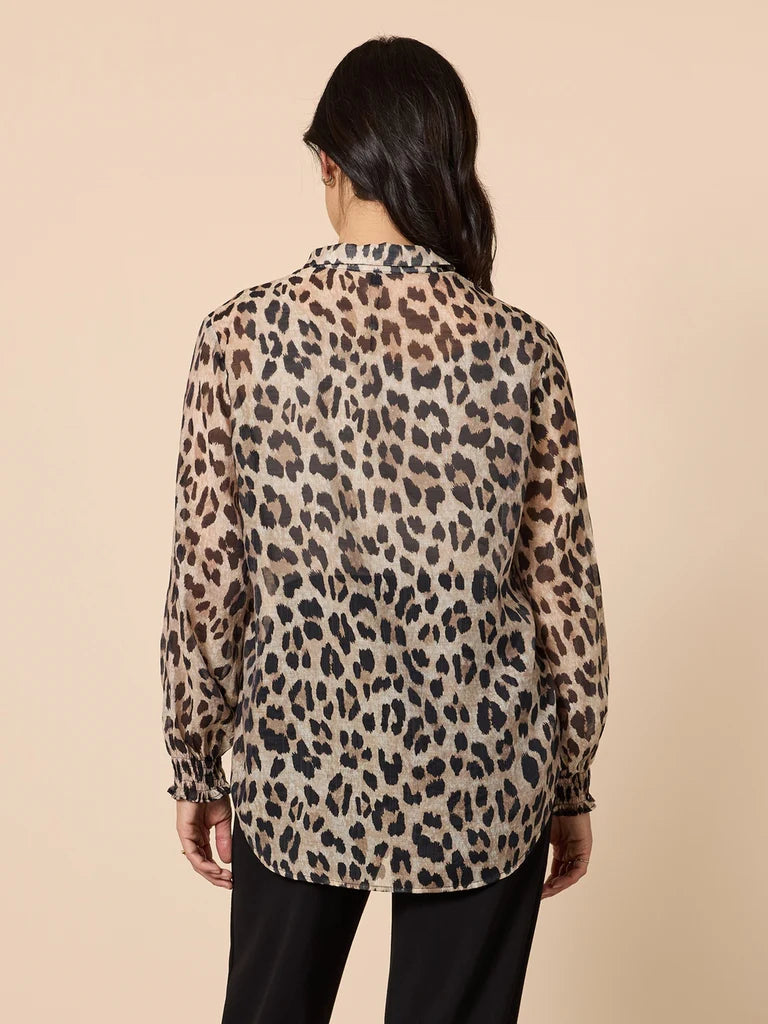 Image of Woman wearing a Gordon Smith leopard print blouse against a beige background